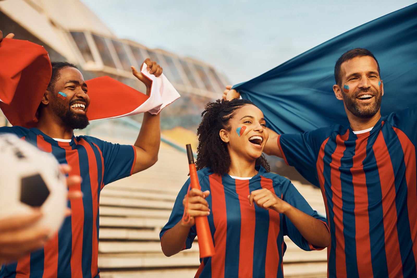 Sports fans celebrating in custom navy and red striped team uniforms — custom team uniform manufacturer