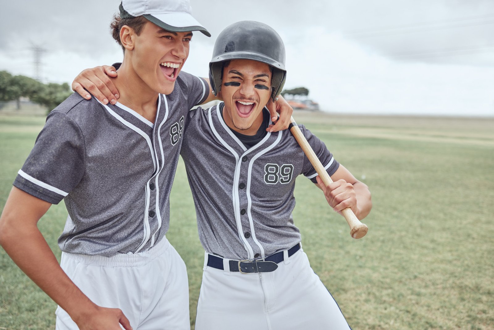 Teen baseball players celebrating in custom gray uniforms on field — youth baseball uniform manufacturer