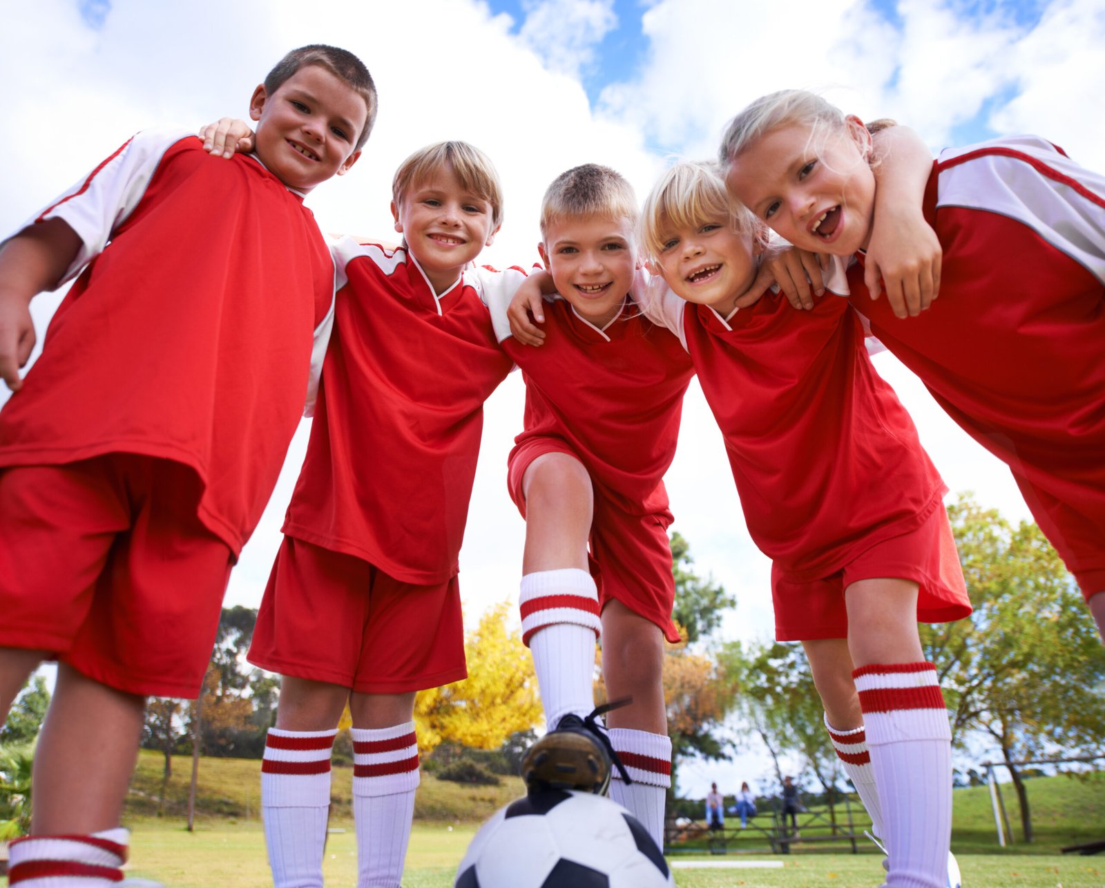 Young children's soccer team in matching red custom uniforms smiling — youth football uniform manufacturer USA | Wearlets