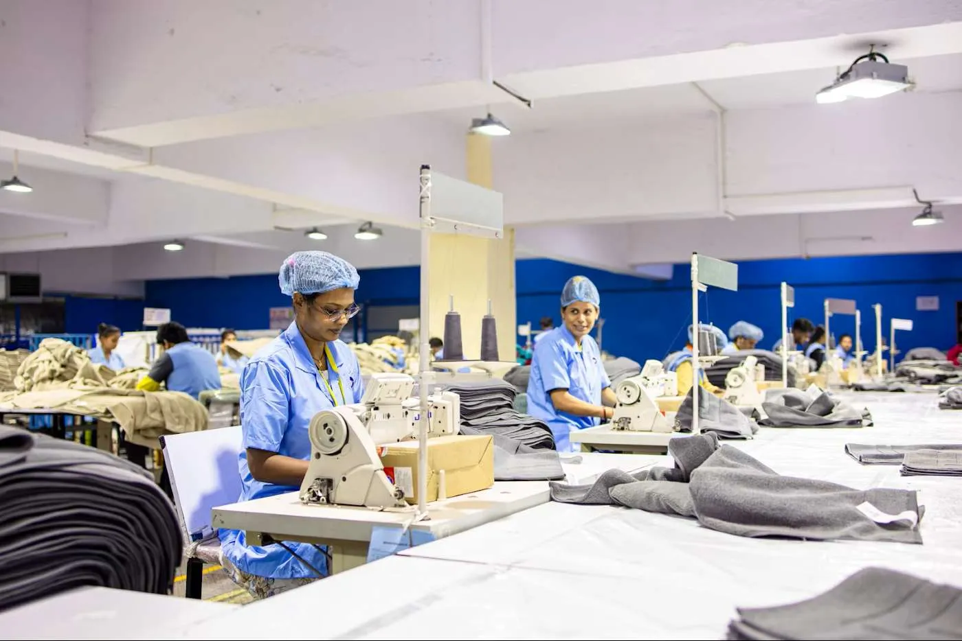 Garment worker sewing fabric on a machine in a manufacturing facility